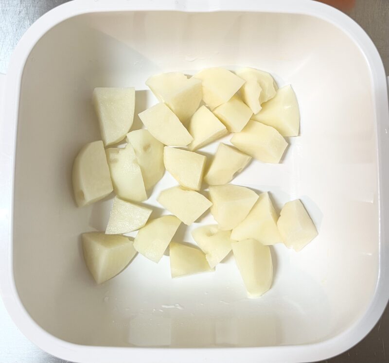 じゃがいもを火が通りやすい小さめの一口大にカットして容器に入れた写真。レンチンで時短調理。