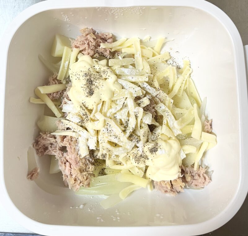 加熱済みのじゃがいもにツナ缶とマヨネーズやチーズなどの調味料を加え、混ぜ合わせる工程。