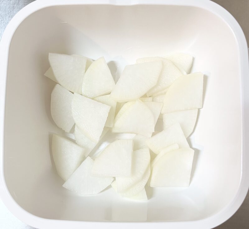 耐熱容器にイチョウ切りにした大根と水大さじ1を入れてレンジで加熱する前の写真。大根を下茹でせずにレンジで調理する様子。