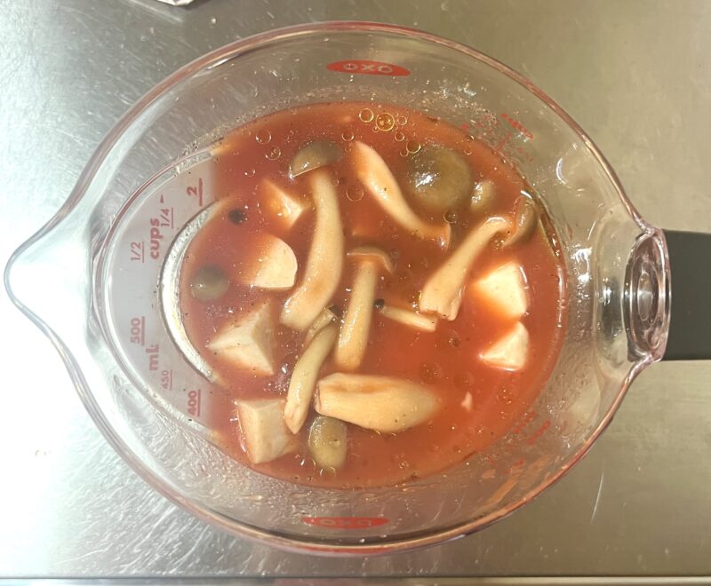 耐熱容器にサラダチキン、しめじ、調味料を入れ、レンジでトマトスープを作るための下準備をしている様子。