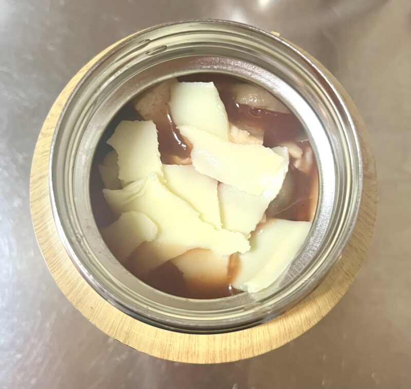 マカロニがはいったスープジャーに熱々のスープとチーズを入れている様子。