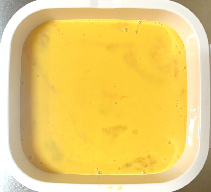 ケチャップライスとスライスチーズの上にといた卵を入れた加熱前の様子