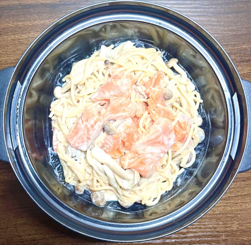 レンジで茹で上がったパスタの上にサーモンとマヨネーズ、牛乳、めんつゆをかけて味付けしている様子