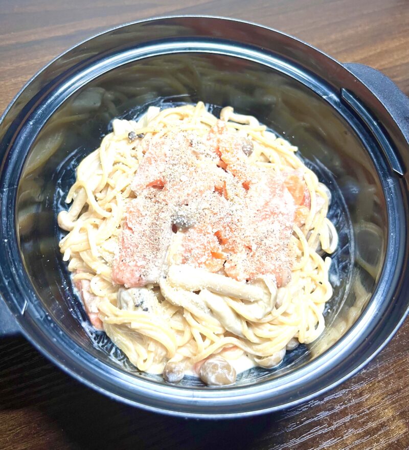レンジだけで作ったサーモンときのこのクリームパスタの上に仕上げ用の粉チーズとブラックペッパーをかけた様子。
濃厚な味のクリームパスタが完成。