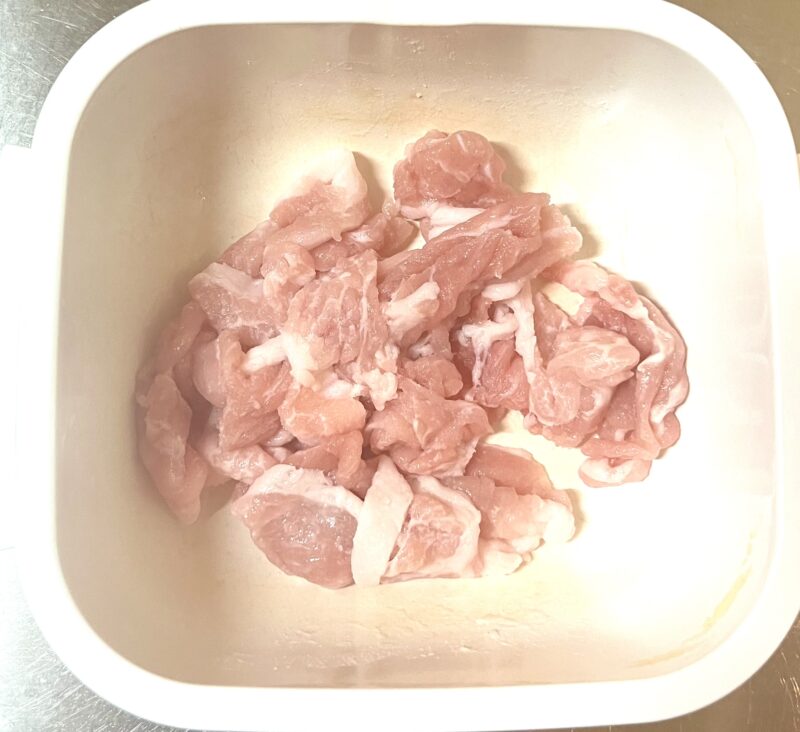 洗い物を減らすために耐熱容器の中で直接豚こま肉に料理酒と米粉を揉み込んでいる様子