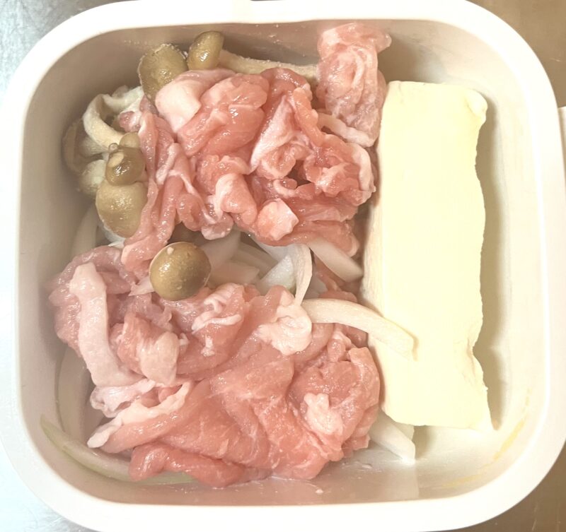 耐熱コンテナに豚こま肉、木綿豆腐、玉ねぎ、しめじ、を入れたレンジ調理前の写真