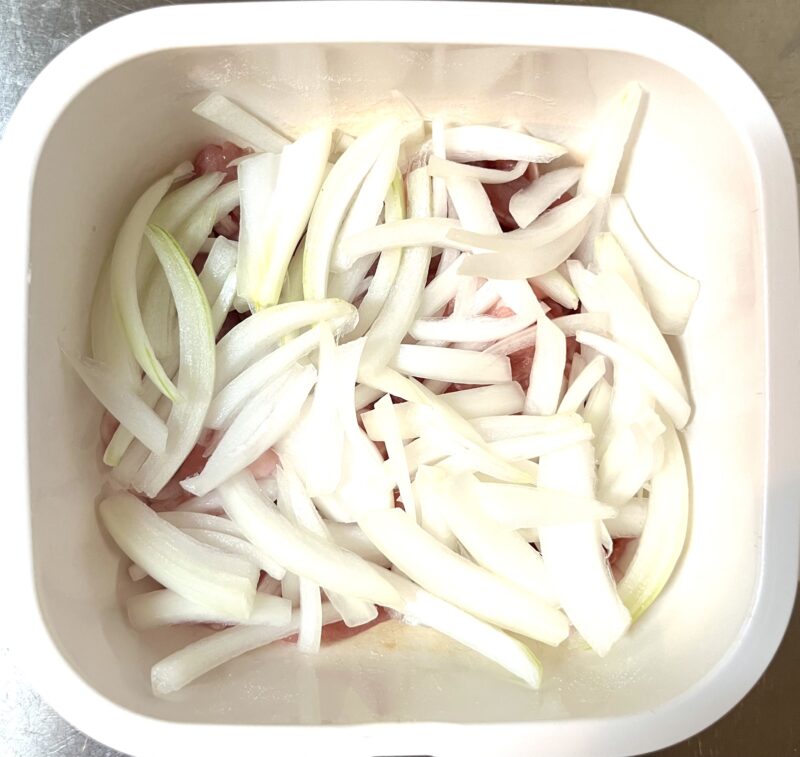 米粉をまぶした豚肉の上に薄切りの生の玉ねぎがたっぷりのせられている様子