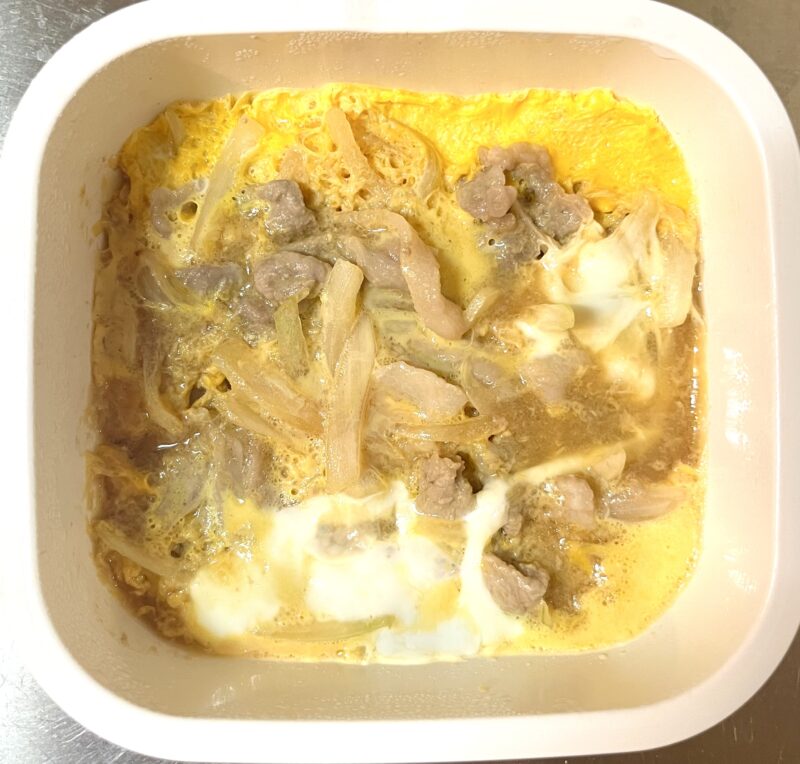電子レンジ加熱が完了し、豚肉と玉ねぎを閉じるように卵がふんわりと固まった状態の耐熱容器内の様子